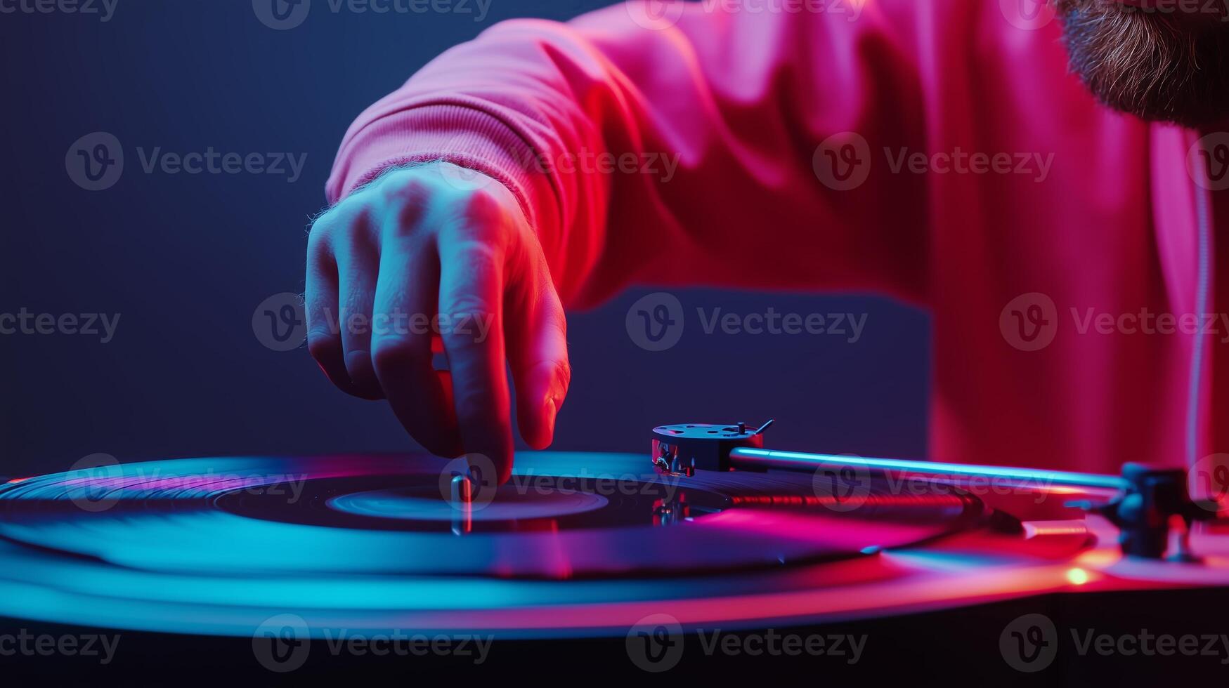 A person spins a vinyl record on a turntable in a dimly lit room with colorful lighting photo