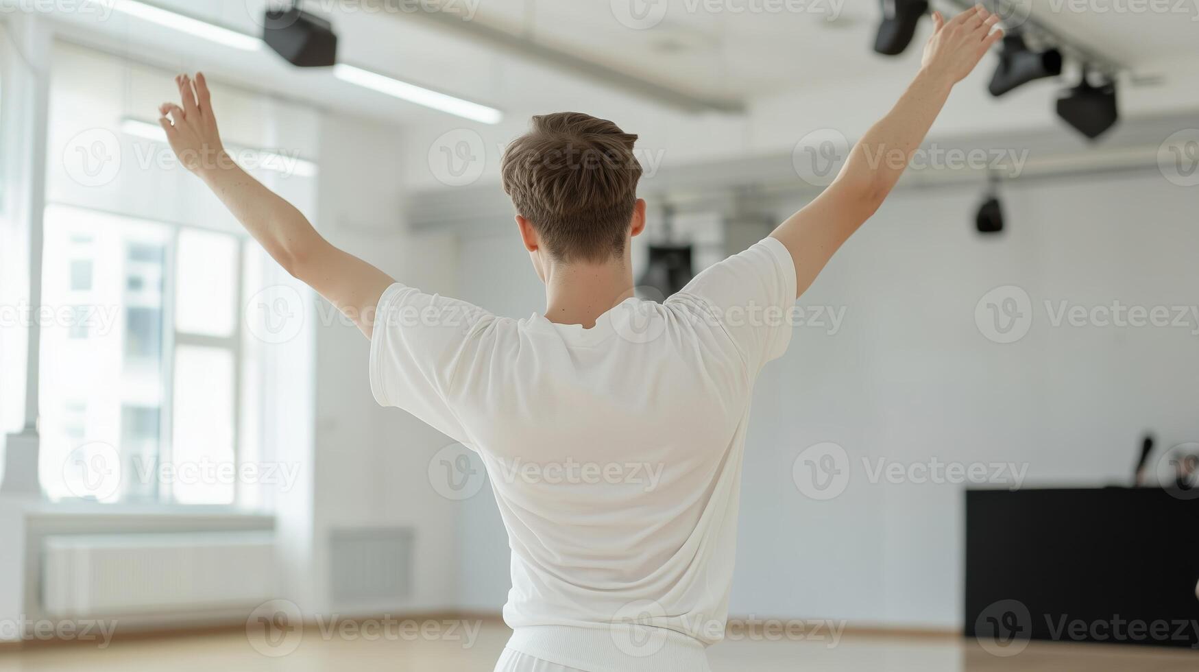 Dancer practicing in a bright studio with arms raised during a rehearsal in the afternoon light photo