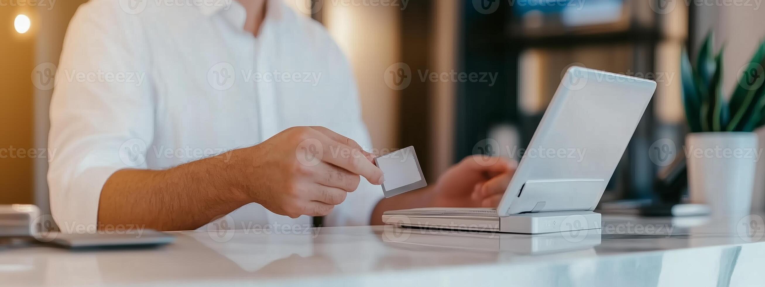 A person making an online purchase using a credit card at a modern workspace with a laptop and plants in the background photo