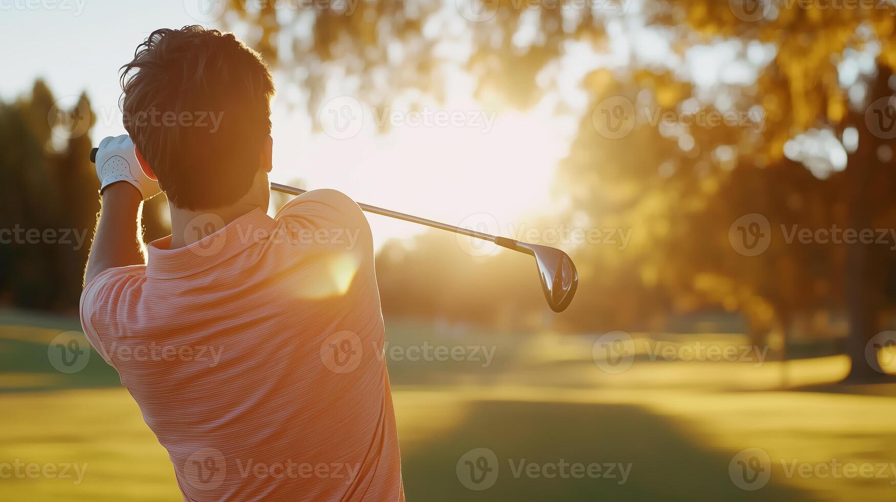 Golfer swinging a club towards the setting sun on a peaceful course during late afternoon in autumn photo