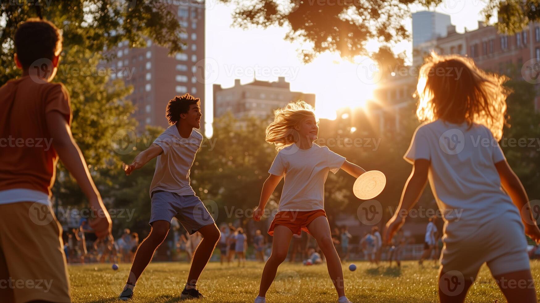 Kids playing frisbee in a sunlit urban park during the late afternoon with city buildings in the background photo