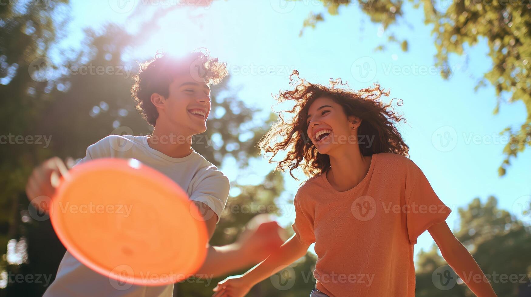 Friends enjoying a sunny day outdoors while playing frisbee in a park filled with trees and bright sunshine photo