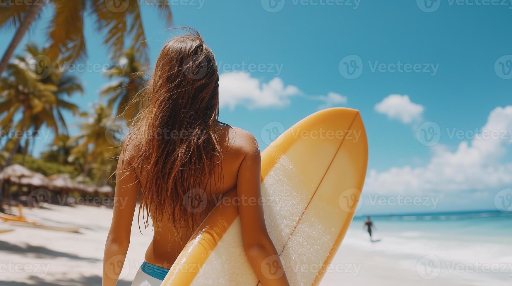 A surfer walks along a tropical beach while holding a surfboard under the bright sun on a clear day photo