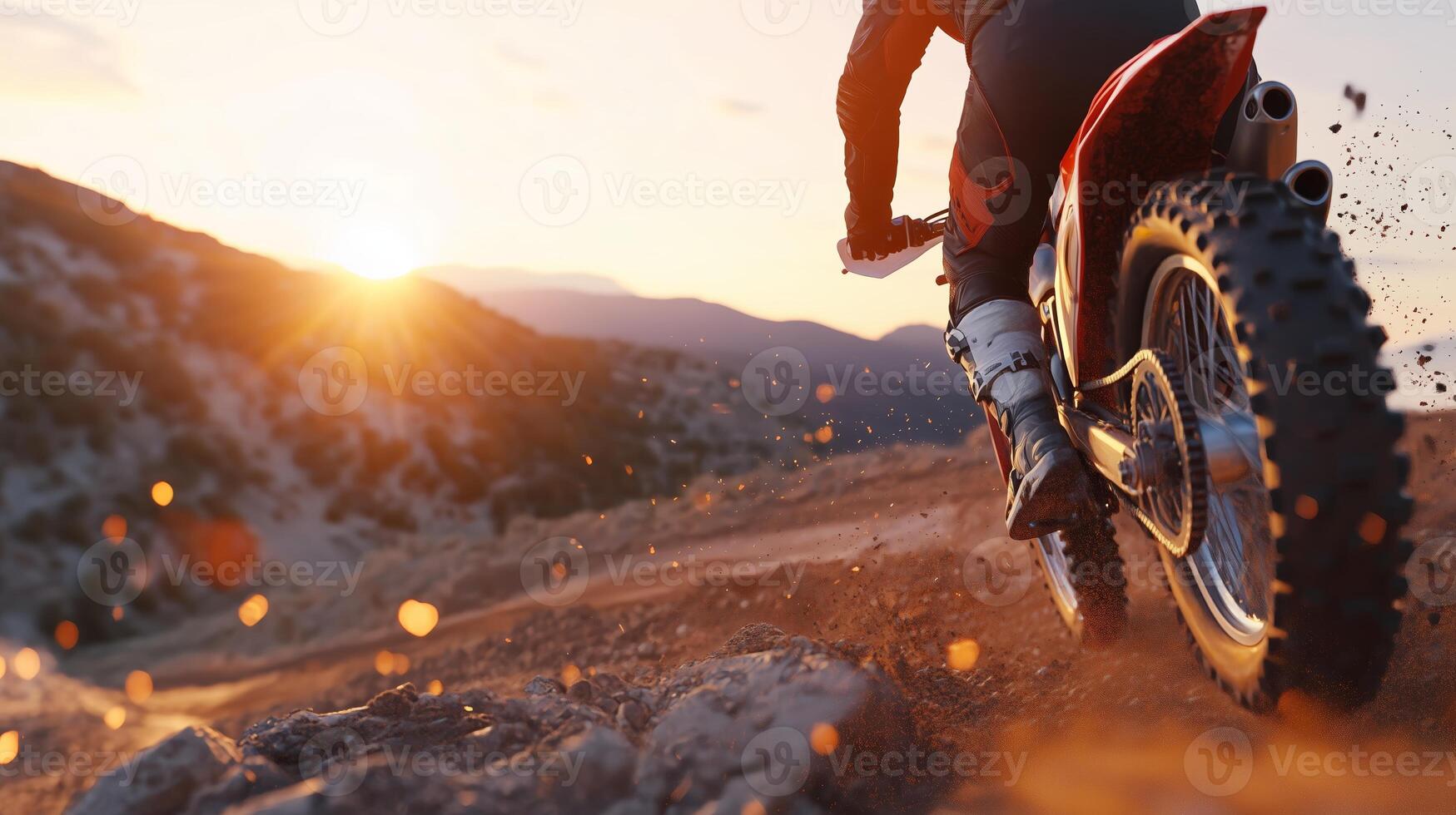 Motocross rider speeding through a rocky terrain at sunset in a mountainous landscape photo