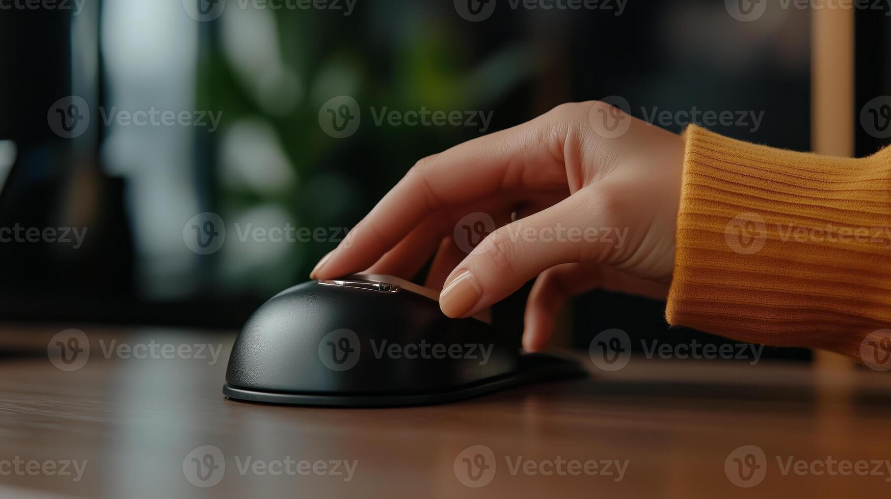 A close-up of a hand using a modern black computer mouse on a wooden desk in a cozy workspace during daylight hours photo