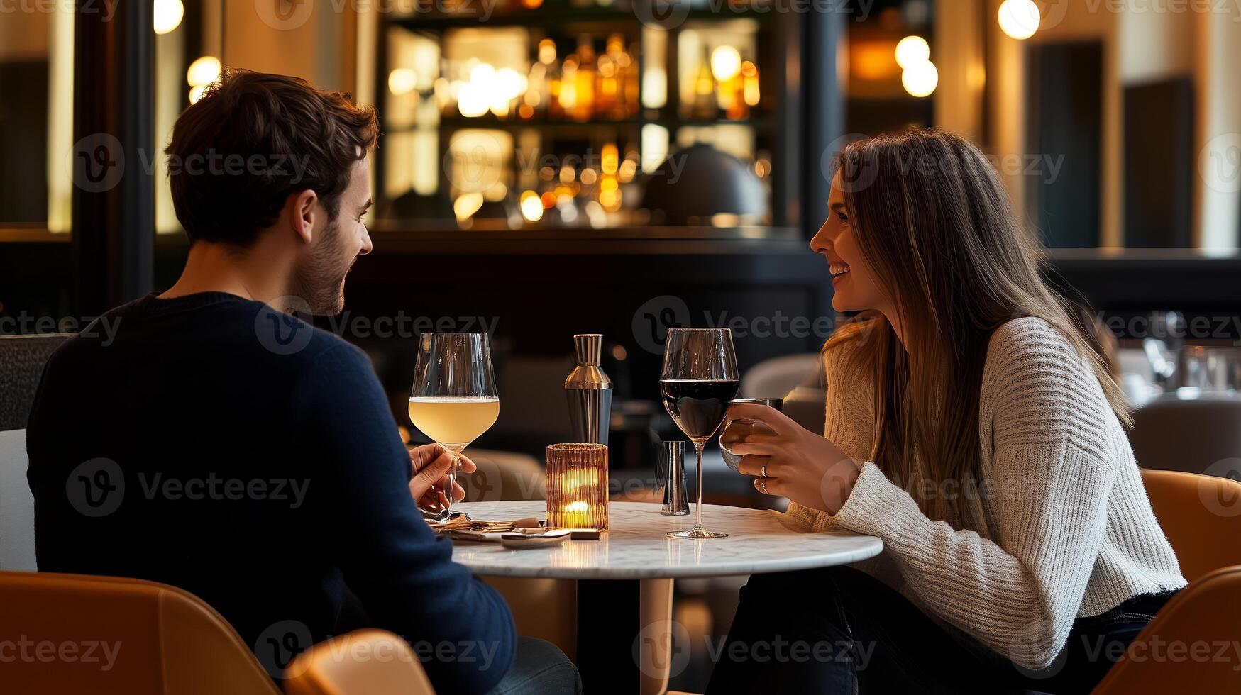 Couple enjoying an intimate dinner conversation at a cozy restaurant in the evening glow with drinks and soft lighting photo
