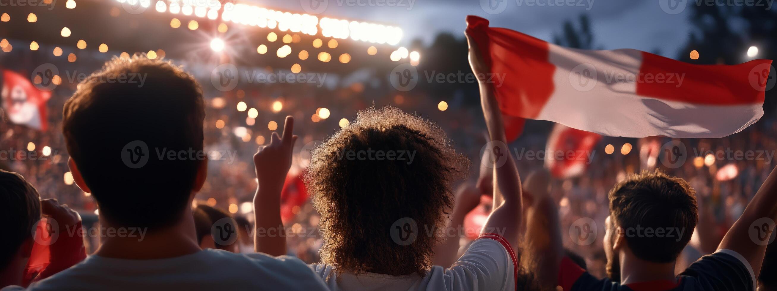 Crowd celebrating with flags during a nighttime sports event at the stadium, creating a vibrant atmosphere of excitement and team spirit photo