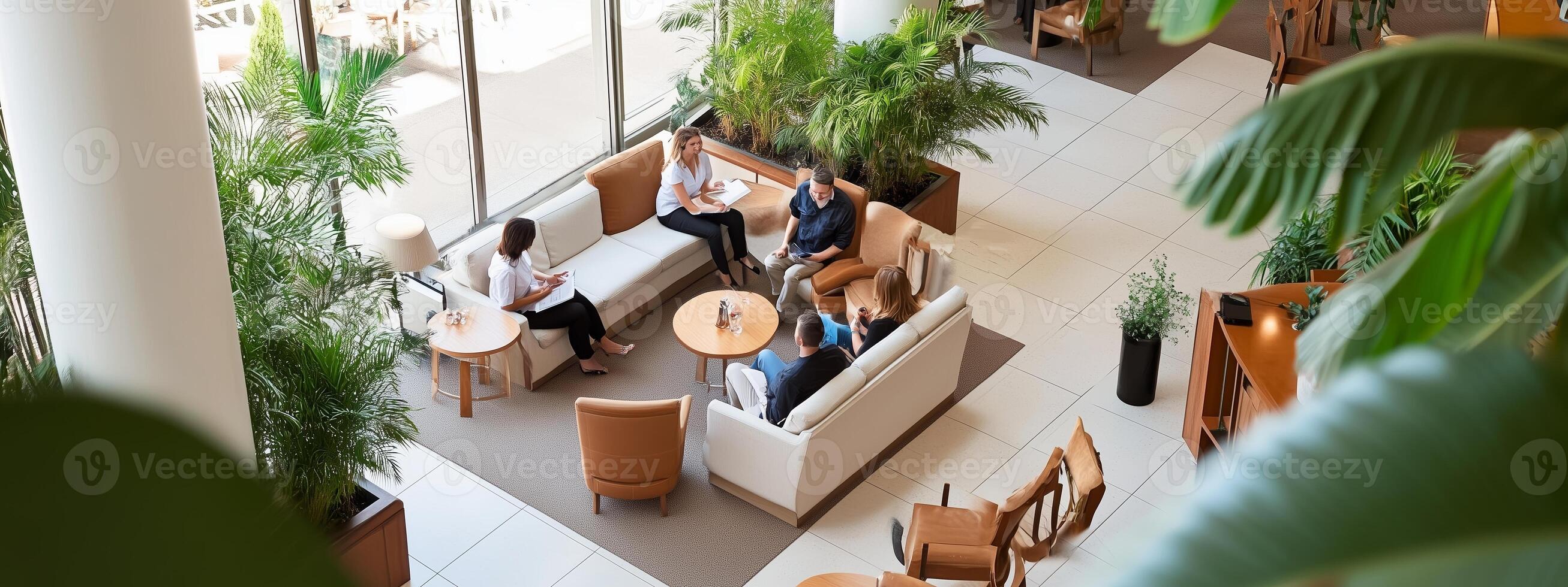 Team members collaborate in a modern office lounge surrounded by greenery during a productive afternoon meeting photo