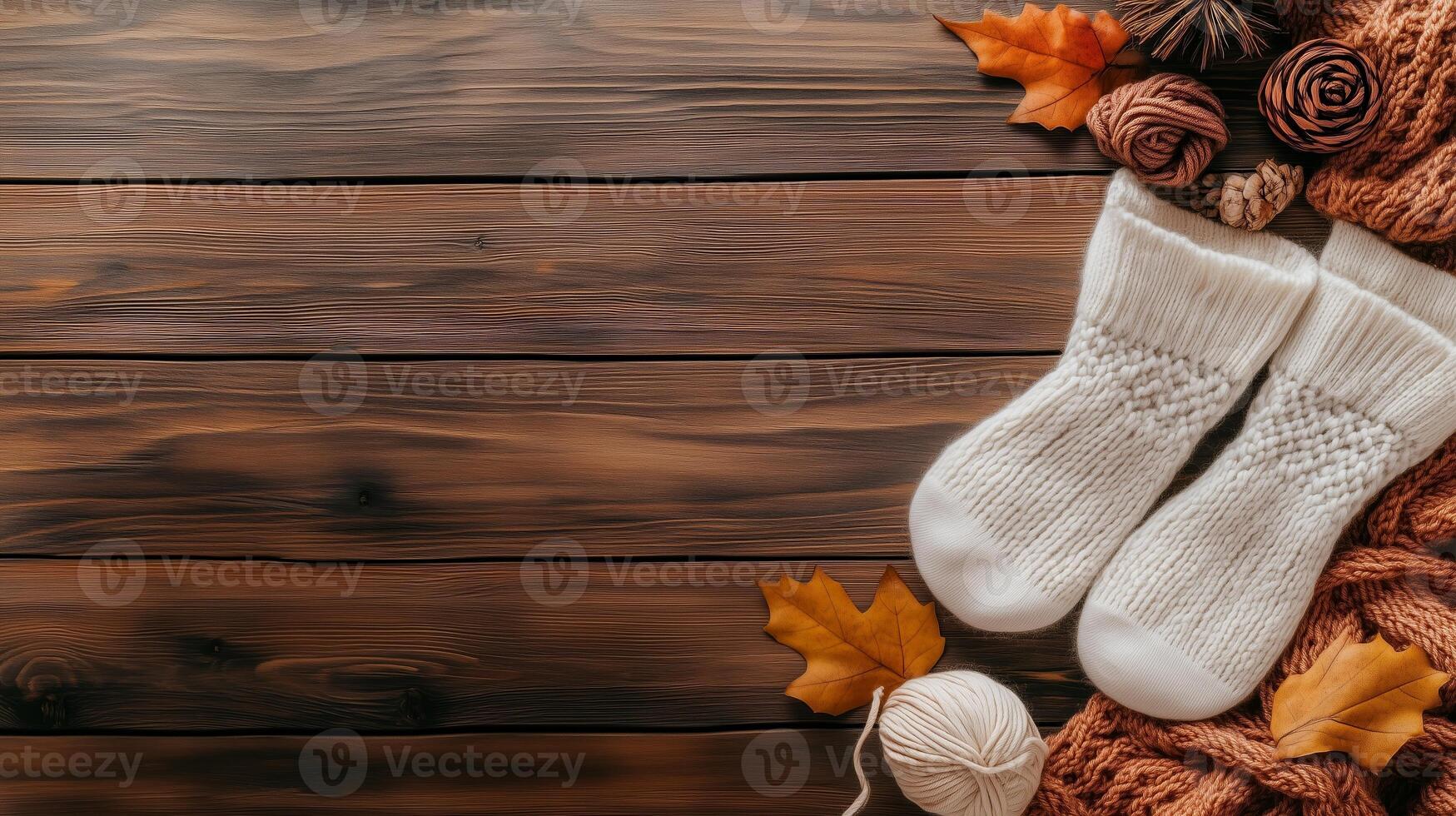 Cozy knitted socks on a wooden table surrounded by autumn leaves and yarn in a warm, inviting setting photo
