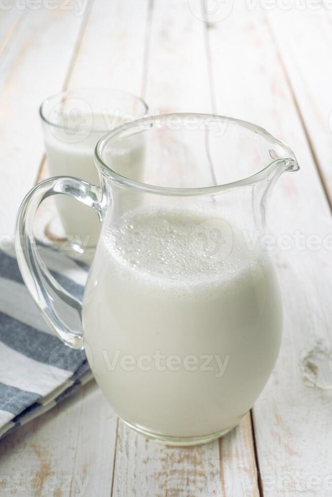 fresh milk in glass jug and glass on wooden background photo