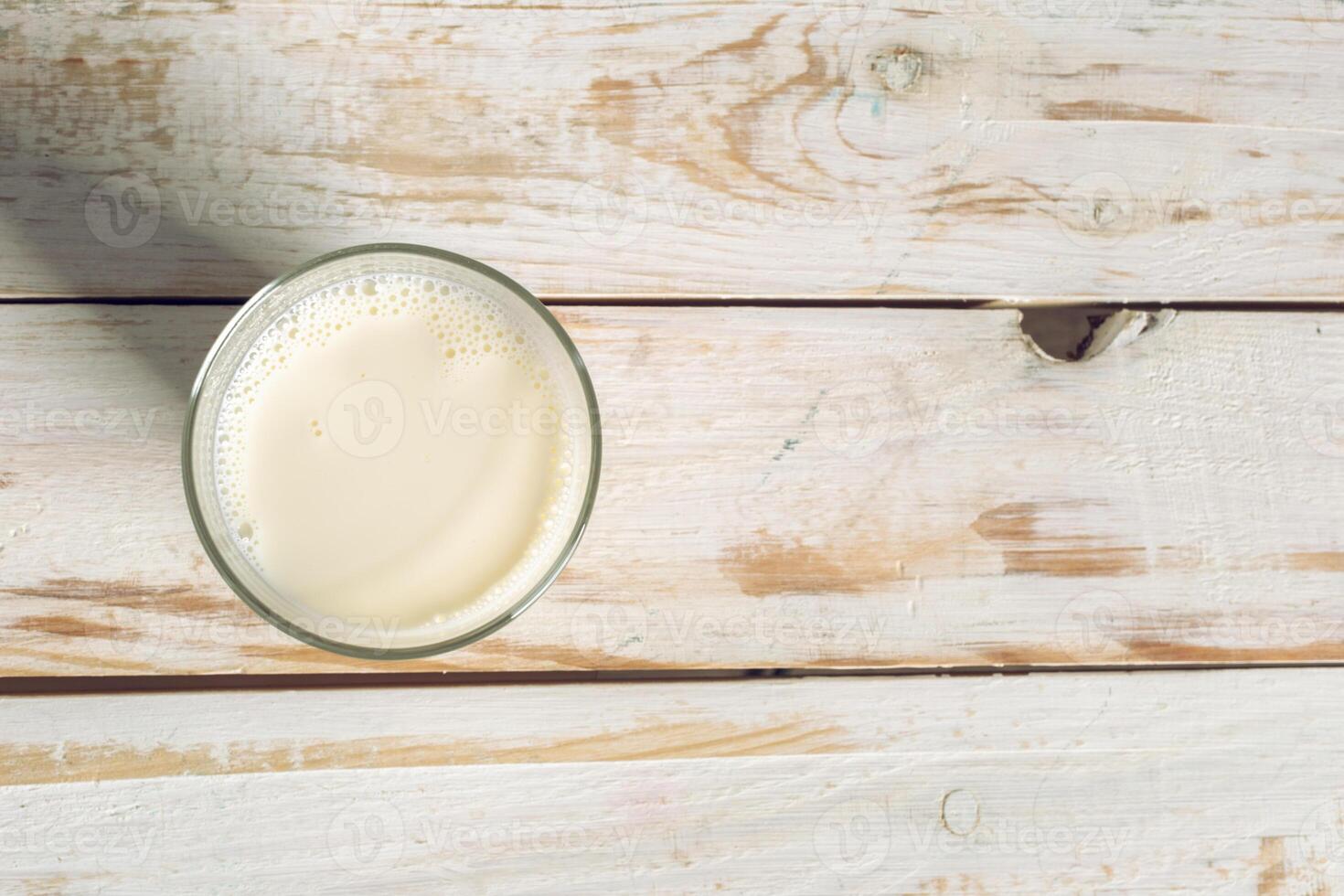 Glass of milk on table on blurred natural background photo