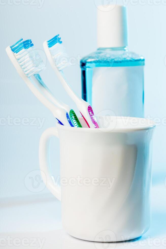Toothbrushes in glass on table on light background photo