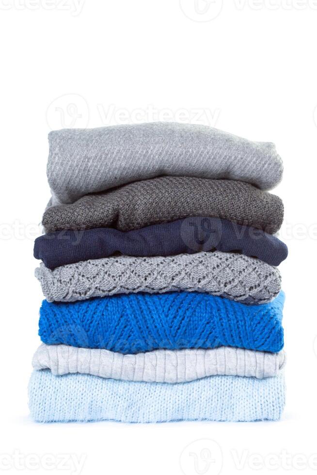 Stack of various sweaters isolated on white background photo