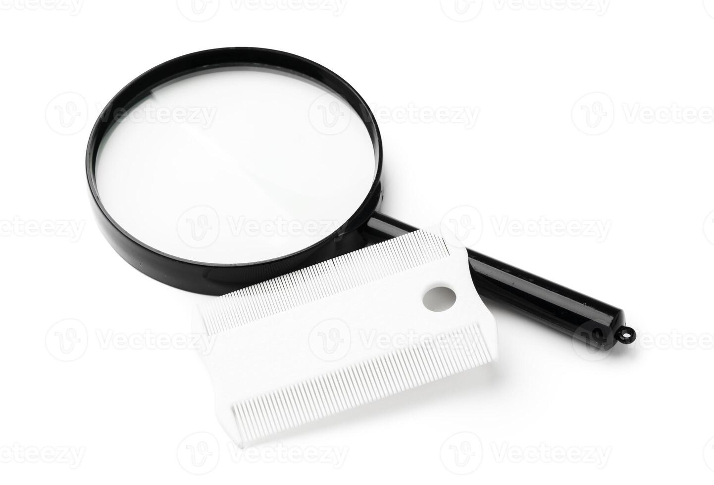 A magnifying glass and lice comb placed side by side on a clean white background photo