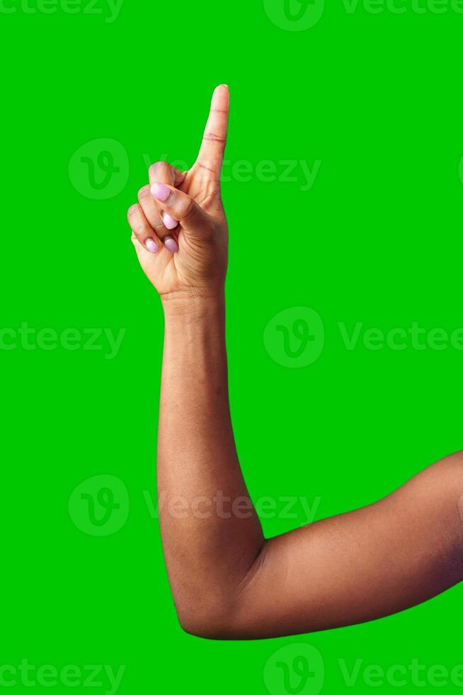 A hand making a gesture with a green background during daylight photo