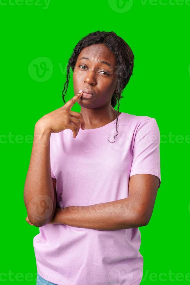 Thoughtful woman pondering in front of a bright green background during a casual moment photo