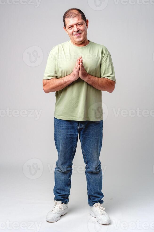 Smiling man standing with hands together in a gesture of greeting or thanks photo