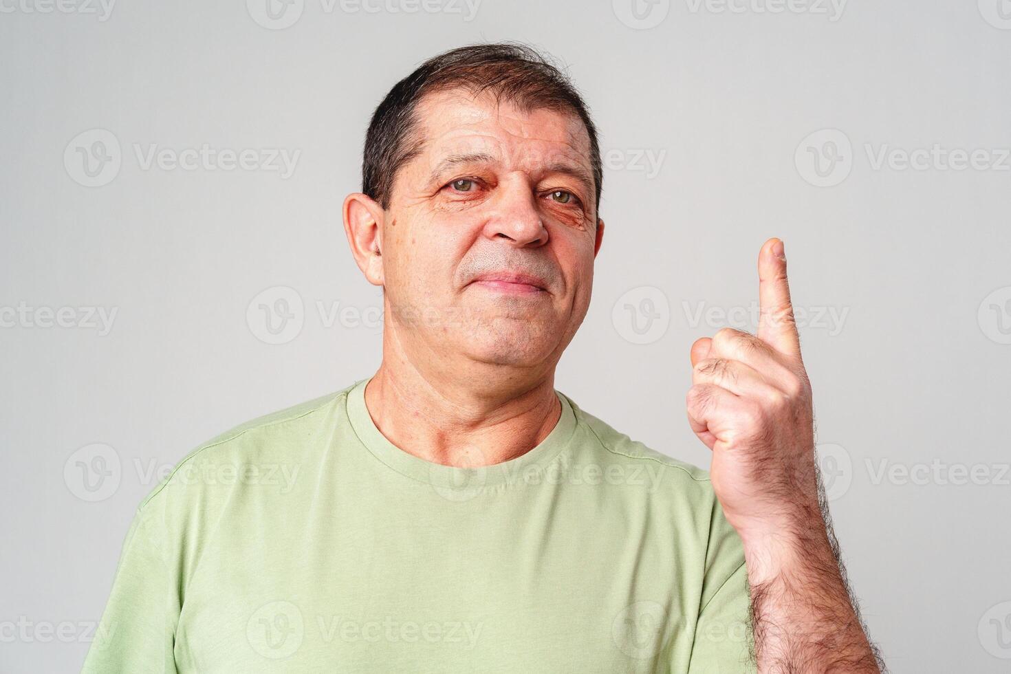 A man in a light green shirt raises his finger, signifying an important message photo
