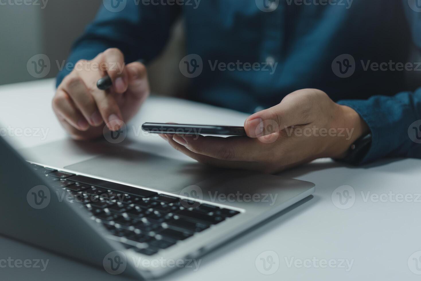 A man is using a laptop and a cell phone photo