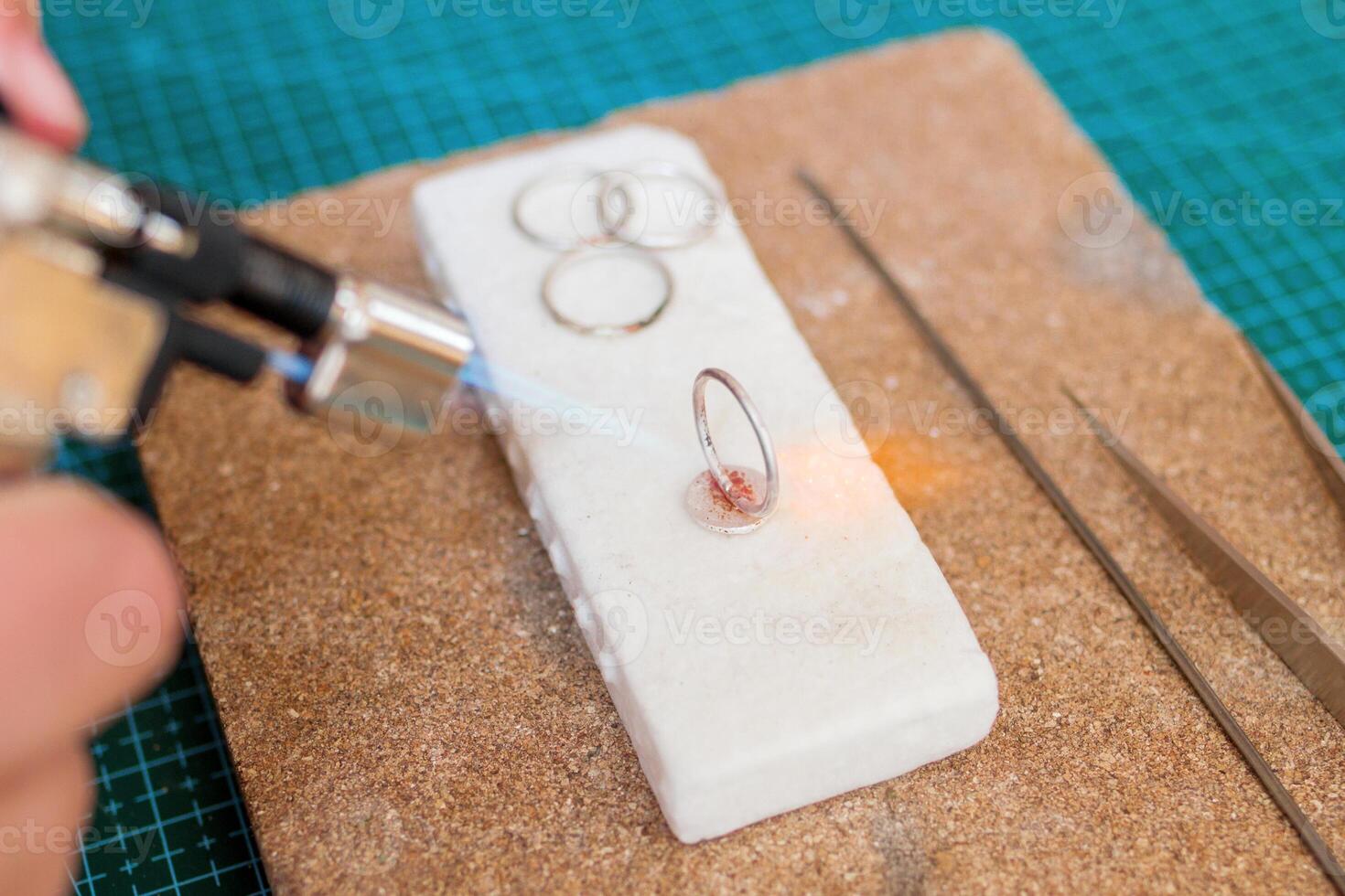 Detailed process of jewelry making with a torch on a white work surface in a creative studio. photo