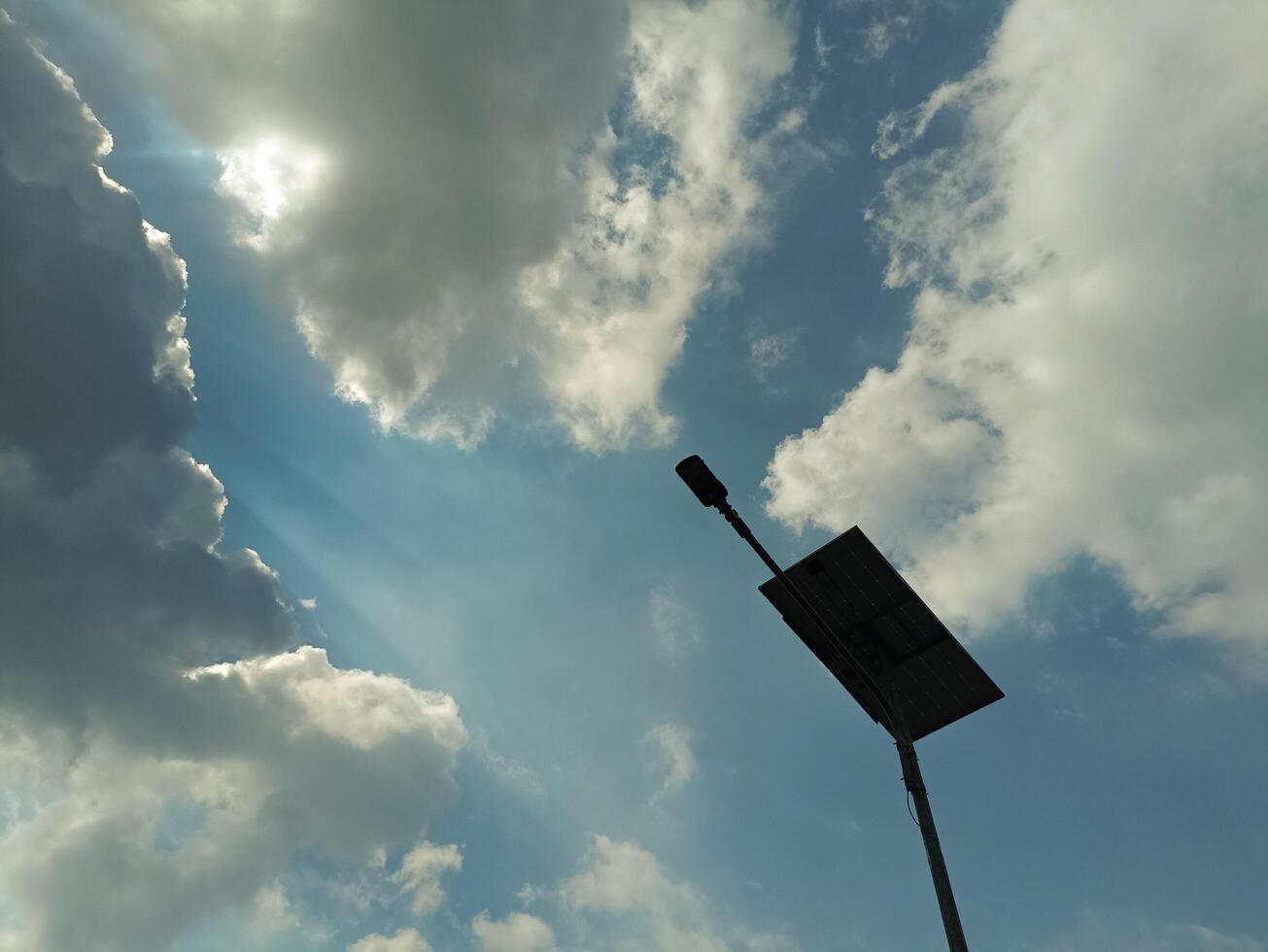 Solar Street Light Against Bright Sunrays Piercing Through Clouds photo