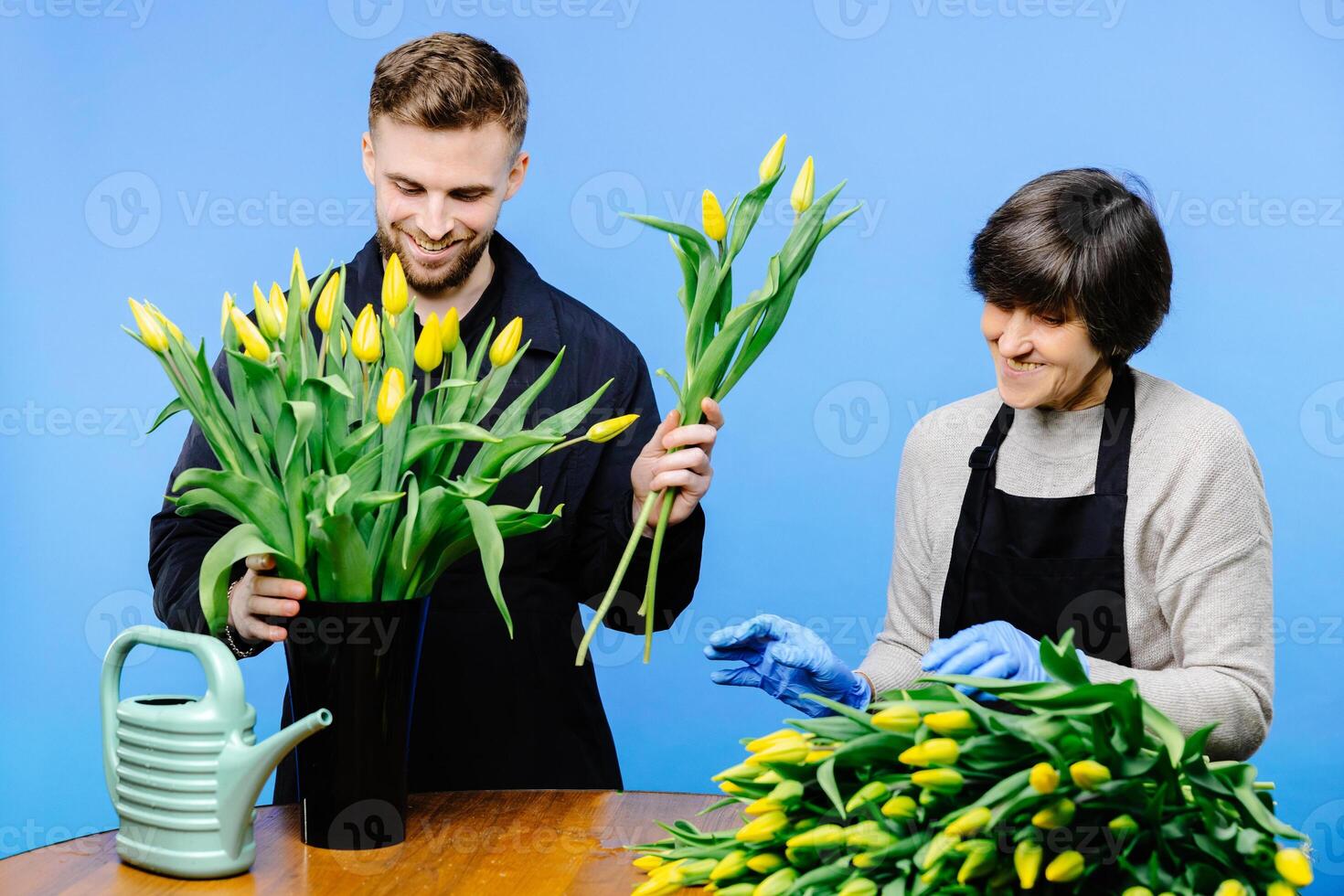 Flower shop. A young guy helps an older woman florist take care of flowers in a flower studio photo