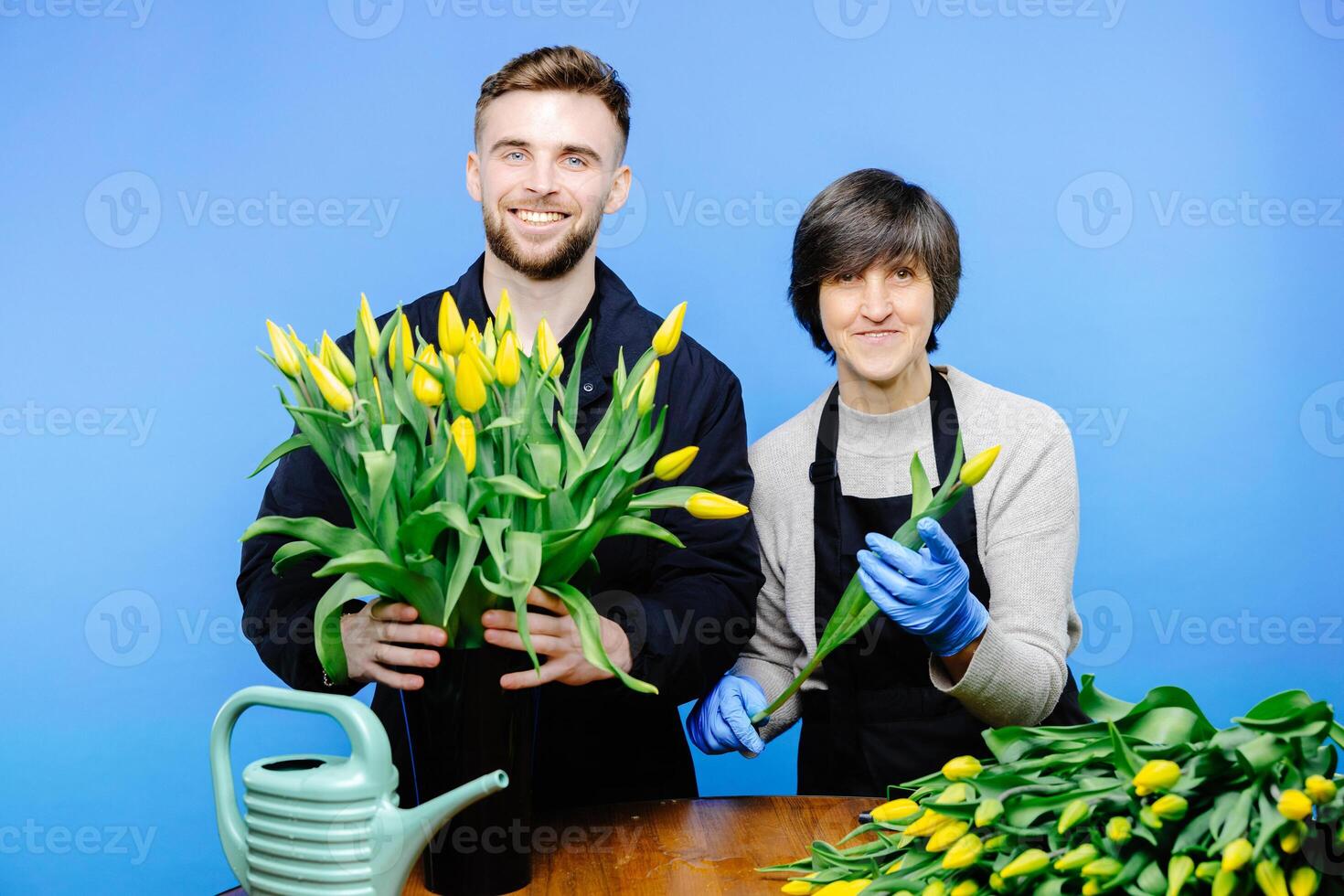 Flower shop. A young guy helps an older woman florist take care of flowers in a flower studio photo