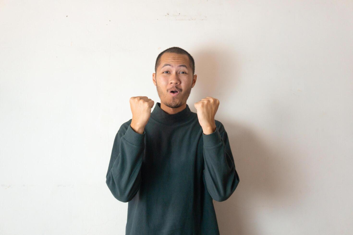 Young men wearing green sweater winning gesture with smile on isolated white background photo