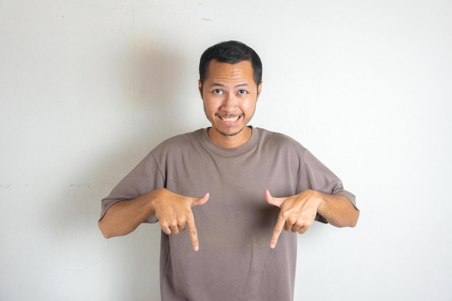 Young Adult Asian men pointing finger to the bottom or down with smiling face and exited expression with isolated white background photo