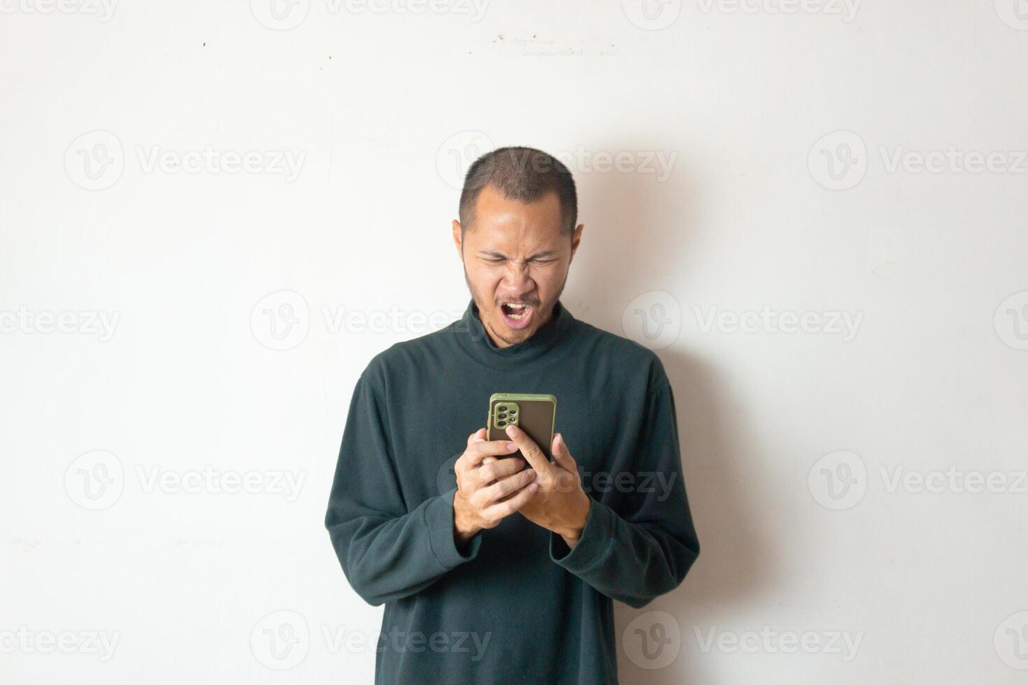 Young asian men wearing winter clothes or sweater is angry while using smartphone on isolated white background photo