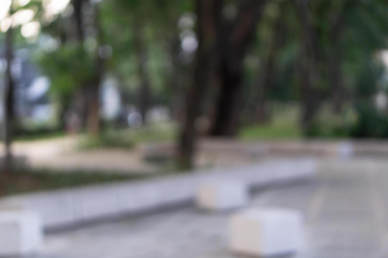 Blurry background of public park outdoors surrounded by trees and sidewalk photo