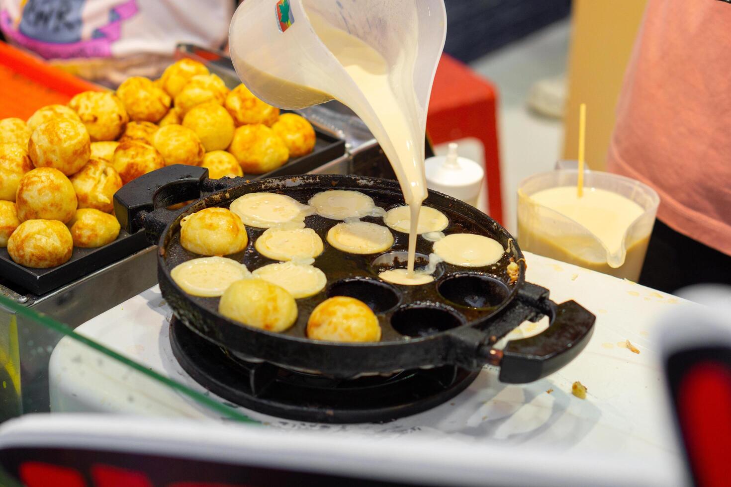 Close up of woman hand cooking takoyaki on food stall in street food in hot pan photo