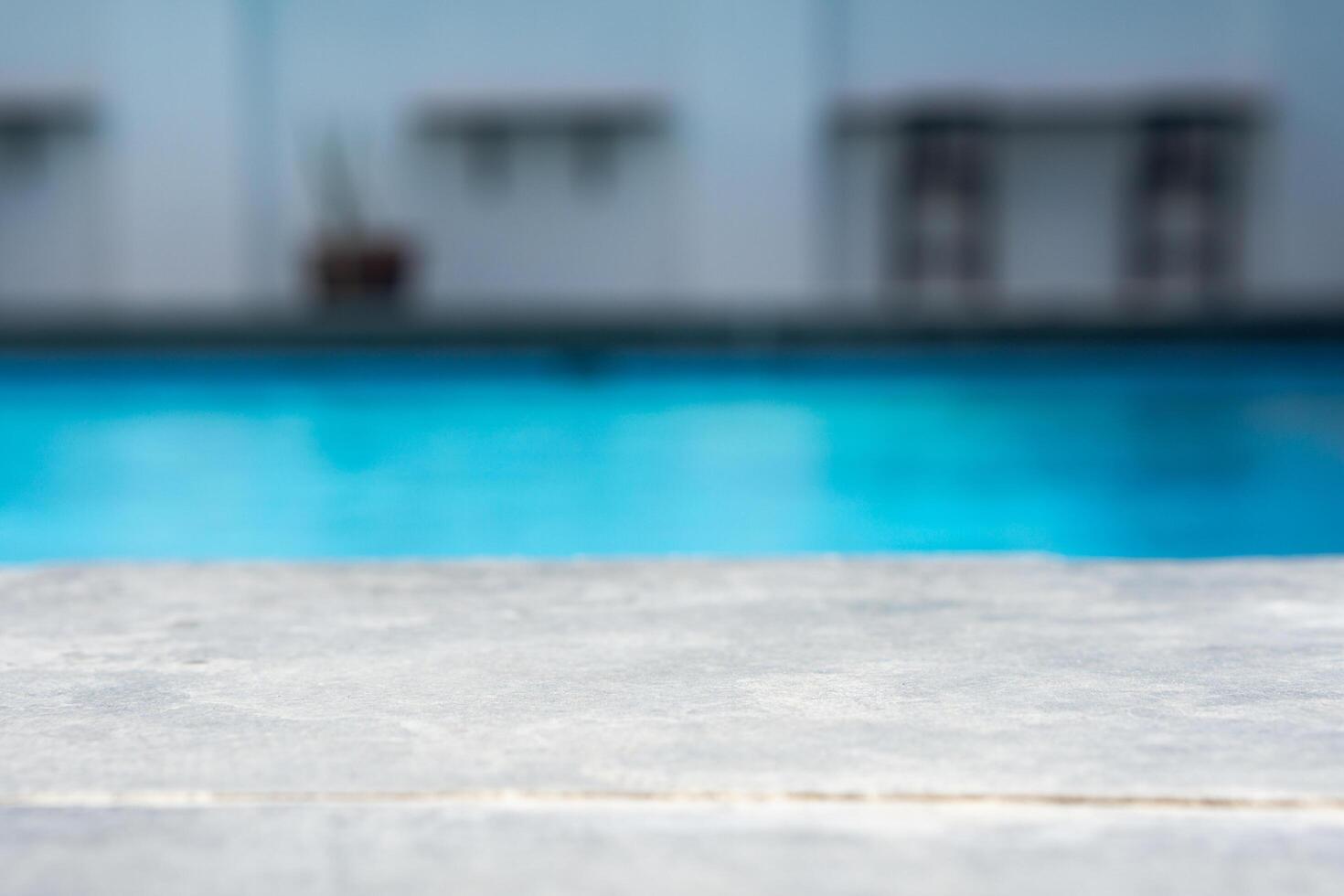 Empty grey ceramic table top and blurred swimming pool in tropical resort in summer banner background photo