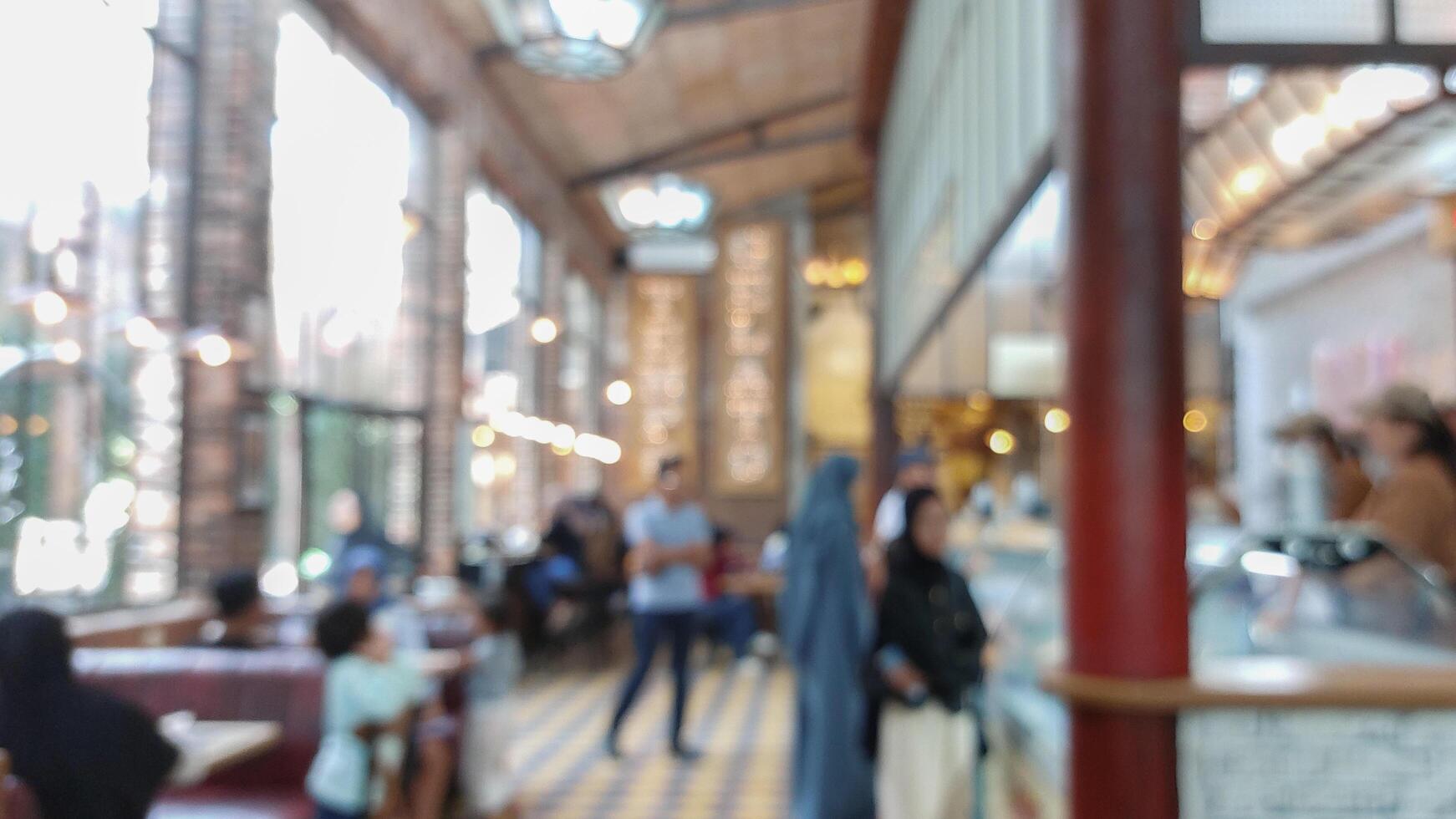 Blurry background of restaurant with light bulb hanging and large window. Customer is paying the bill in cashier photo