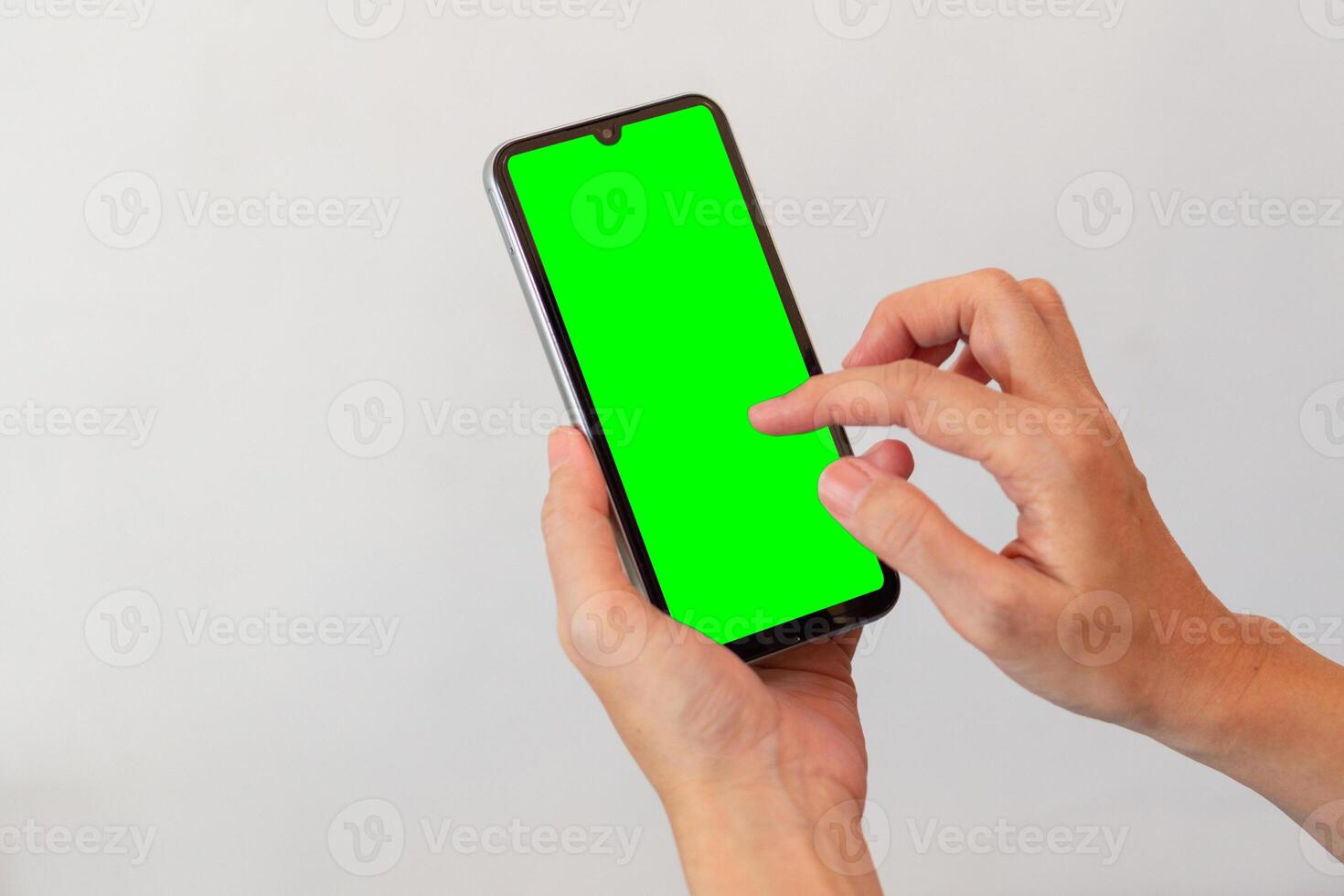 women hand holding smart mobile phone with blank green screen on isolated white background photo