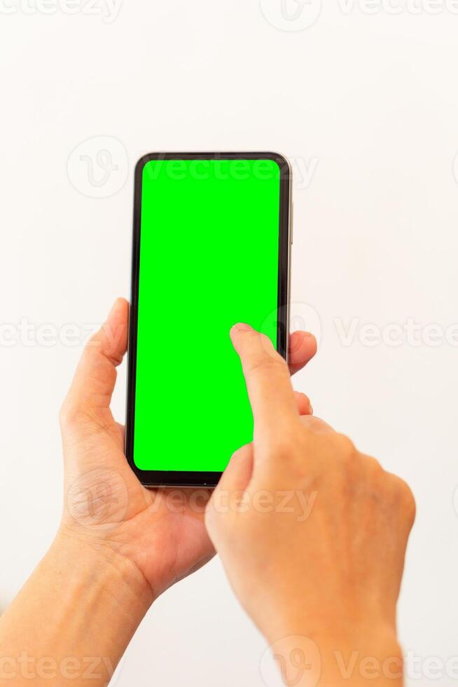women hand holding smart mobile phone with blank green screen on isolated white background photo