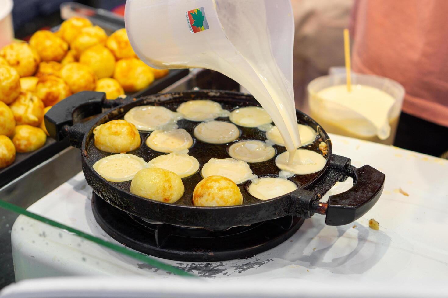 Close up of woman hand cooking takoyaki on food stall in street food in hot pan photo