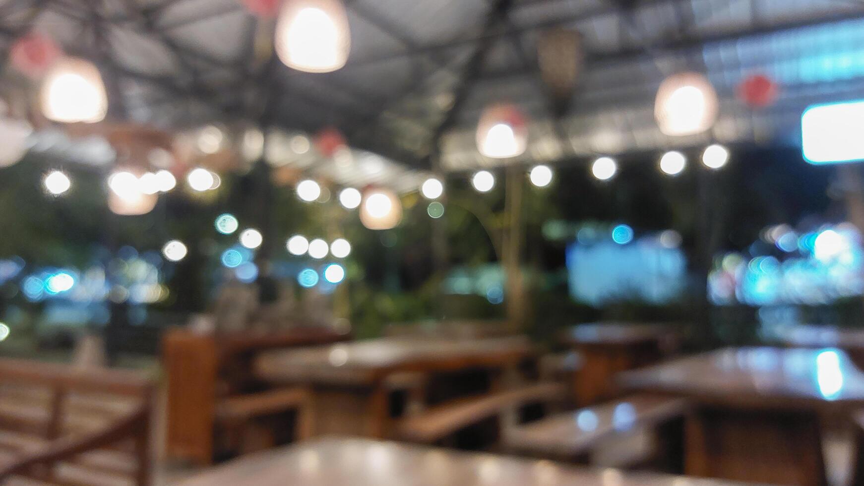 Blurry background of empty restaurant with light bulb and wooden table and wooden chair photo