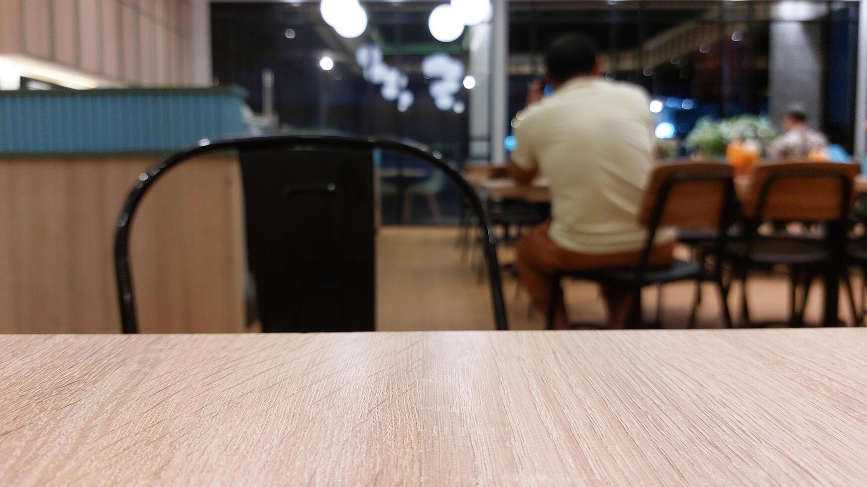 Blurry background of restaurant with wooden table in front for displaying product photo