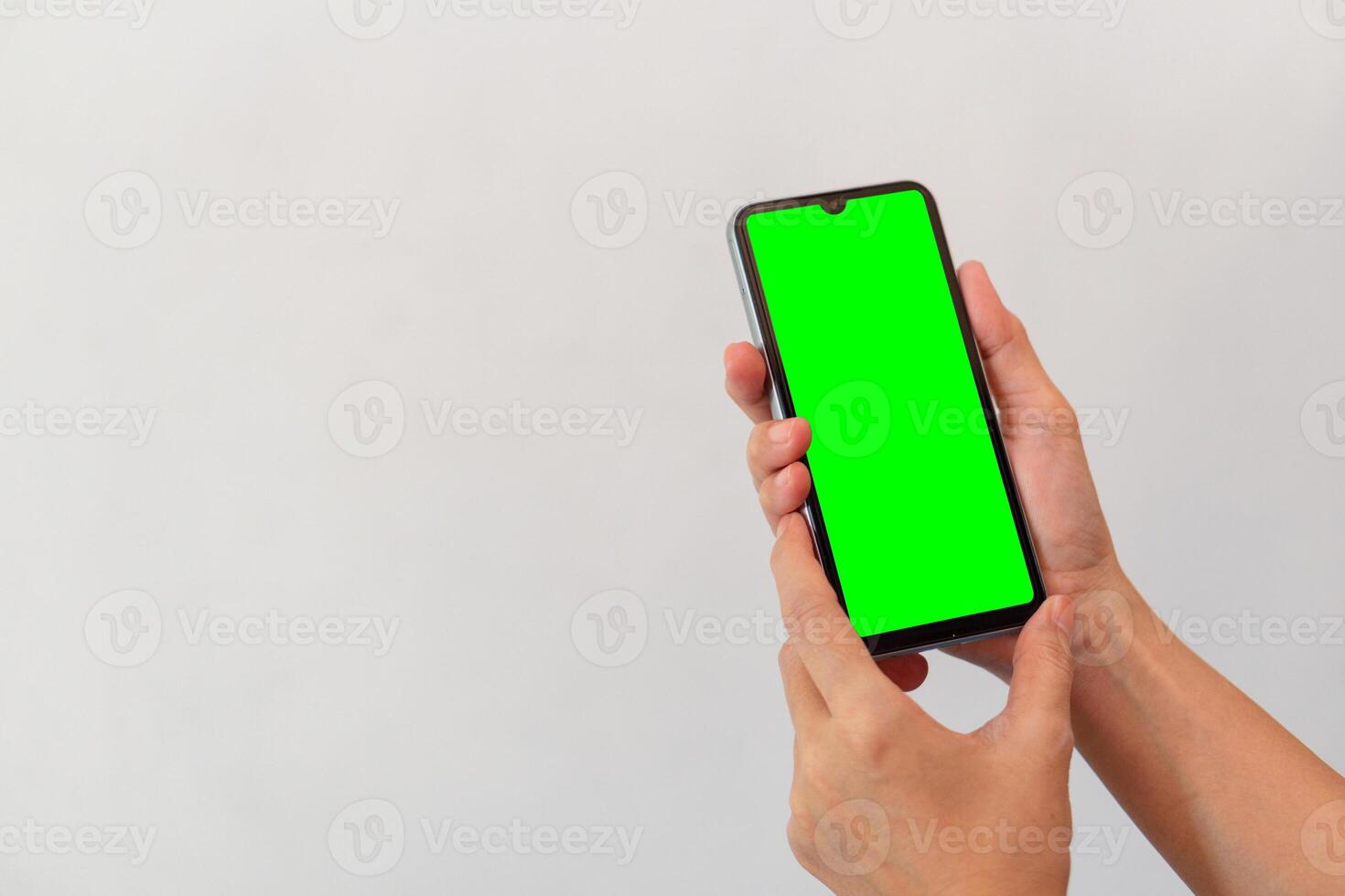 women hand holding smart mobile phone with blank green screen on isolated white background photo