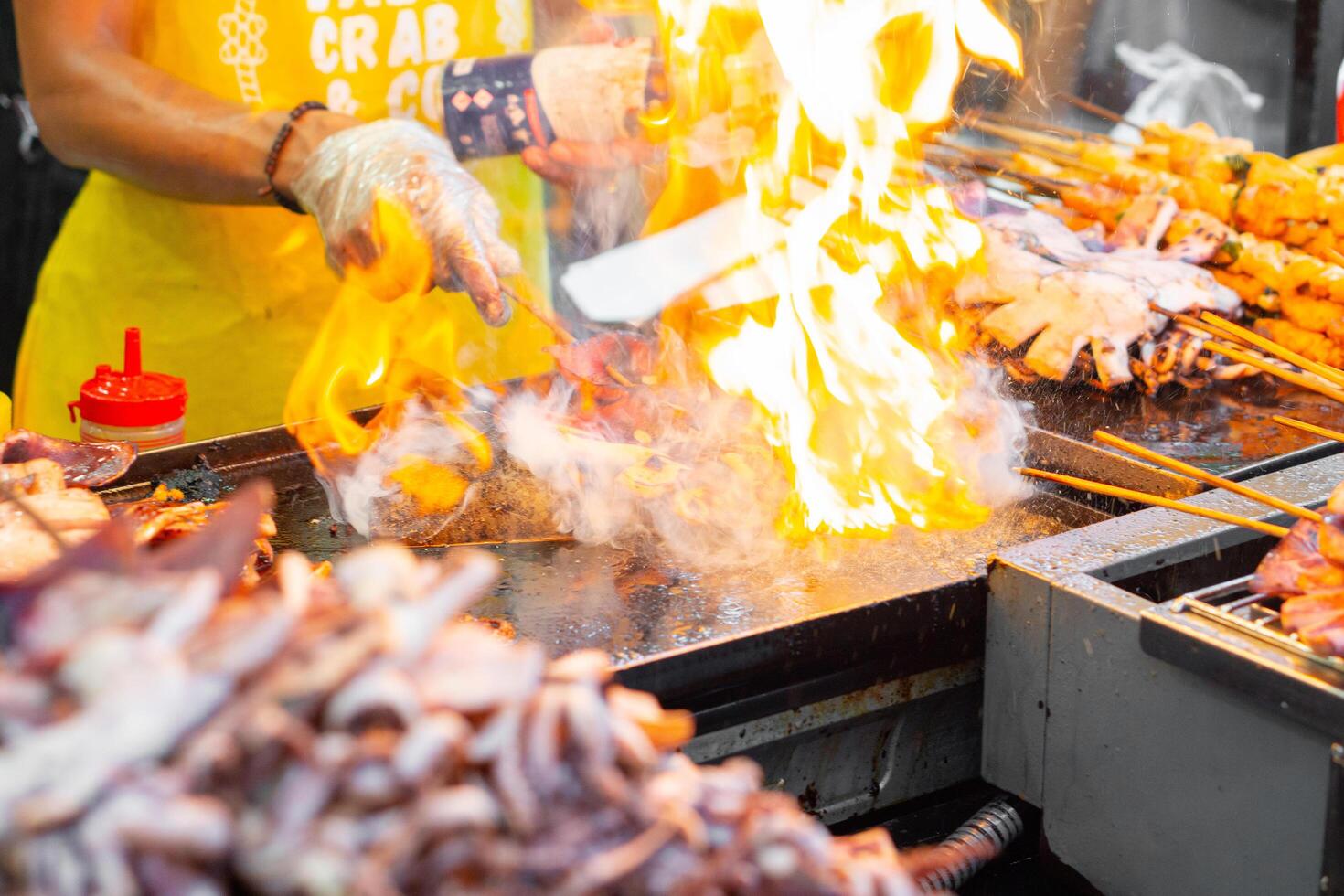 Chef is grilling squid on barbeque with fire on hot pan street food photo