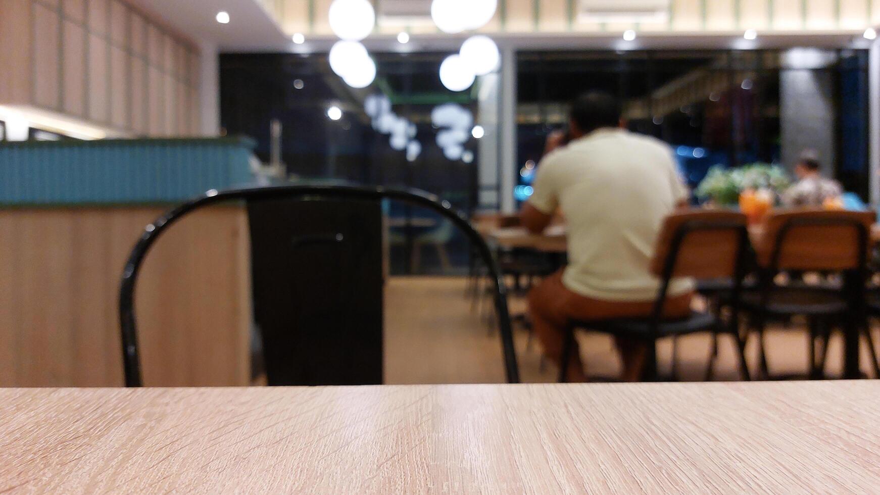 Blurry background of restaurant with wooden table in front for displaying product photo