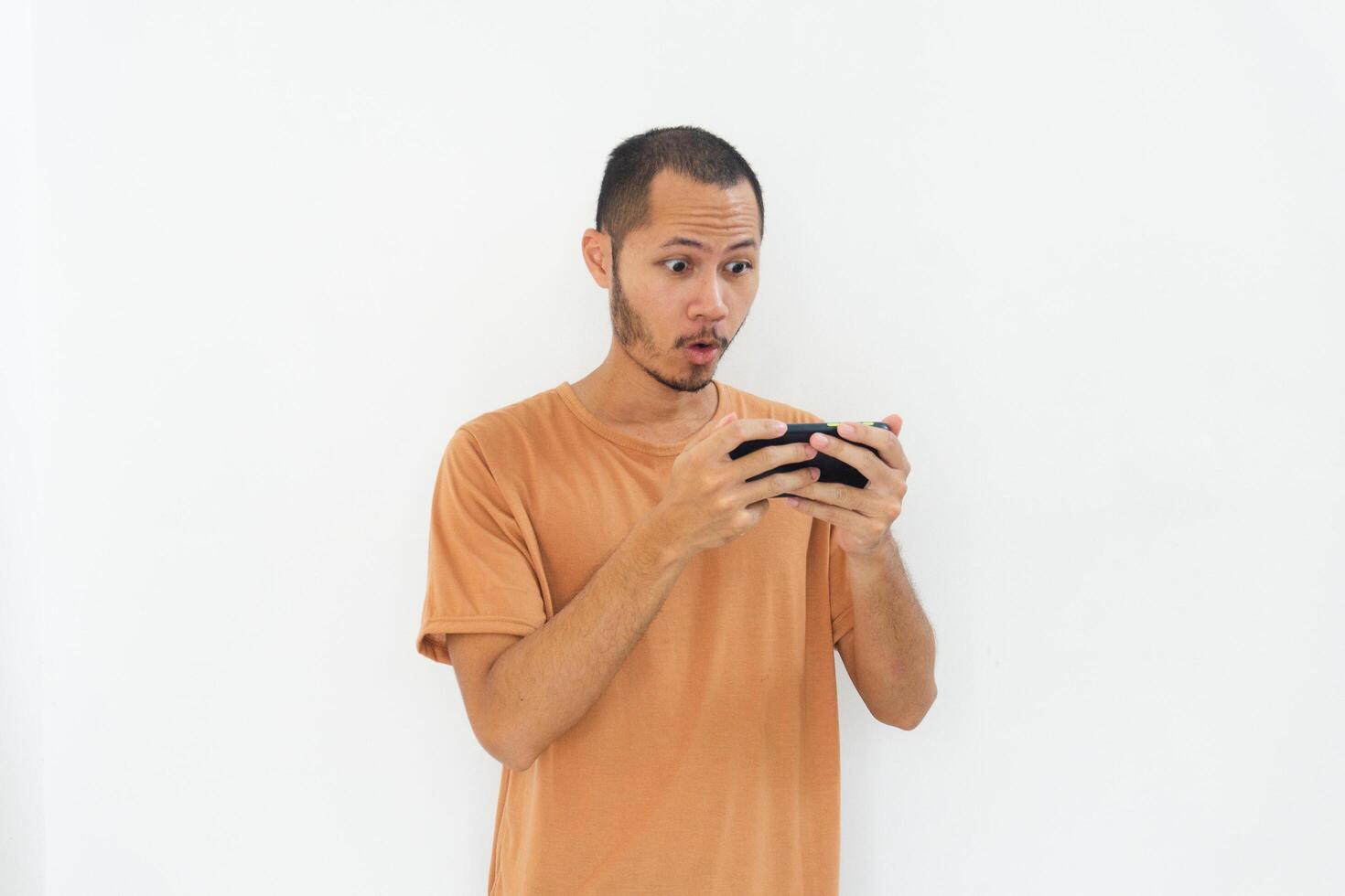 Young men wearing orange shirt is happy playing game using phone on isolated white background photo