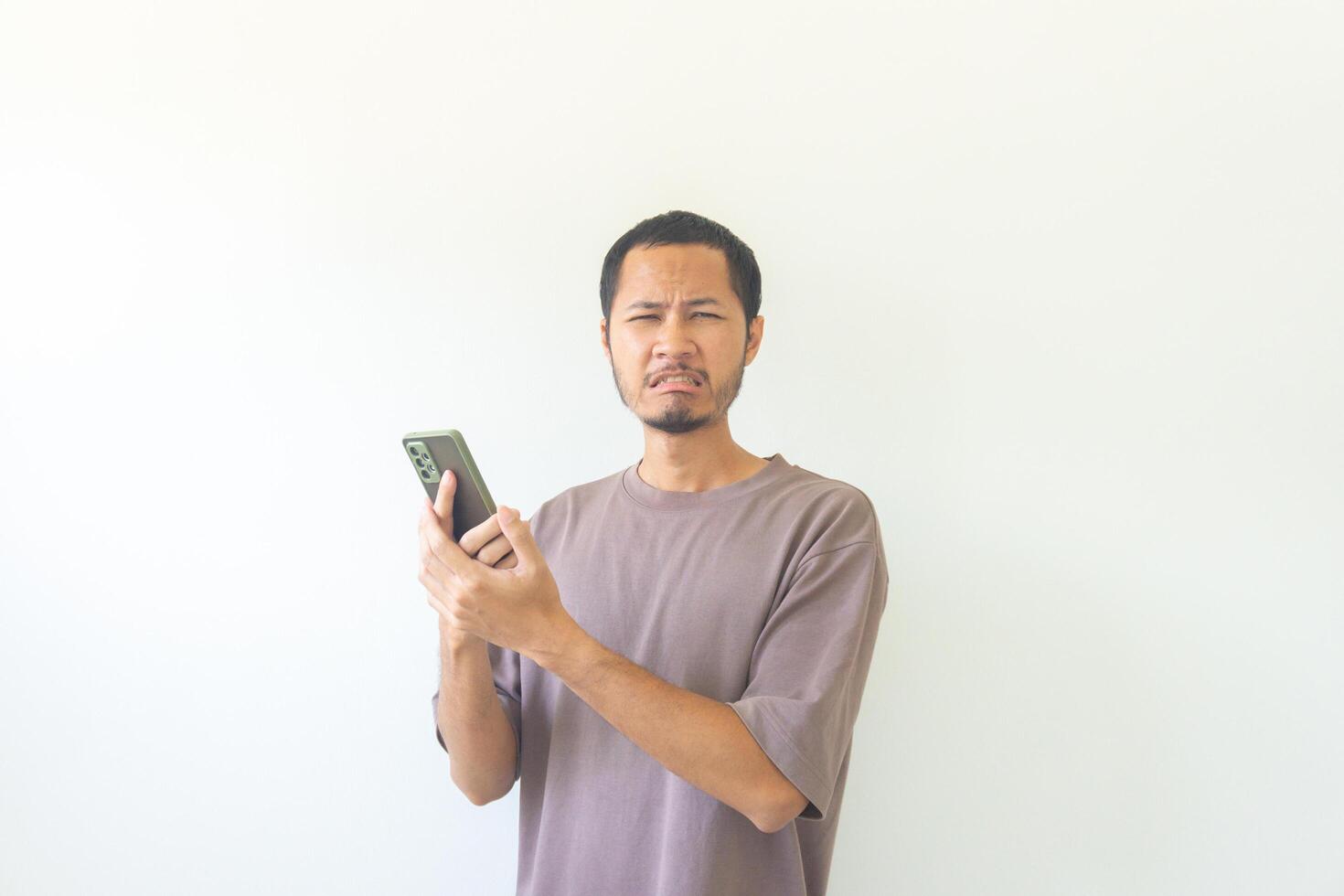 Young asian men sad while holding smartphone on isolated background photo