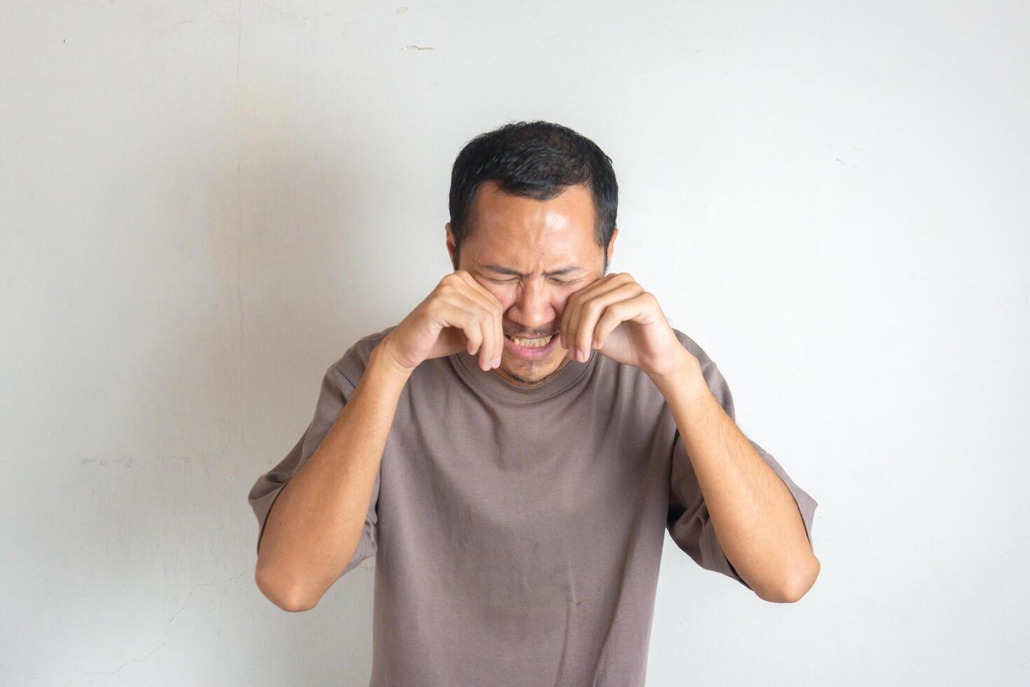 Young men wearing purple shirt is crying on isolated white background photo
