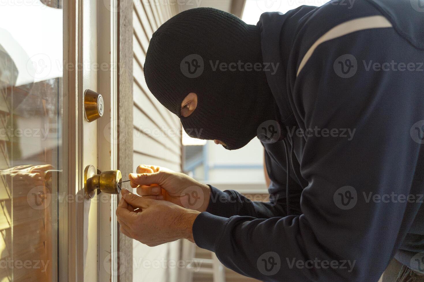 Masked burglar picking lock of front door photo