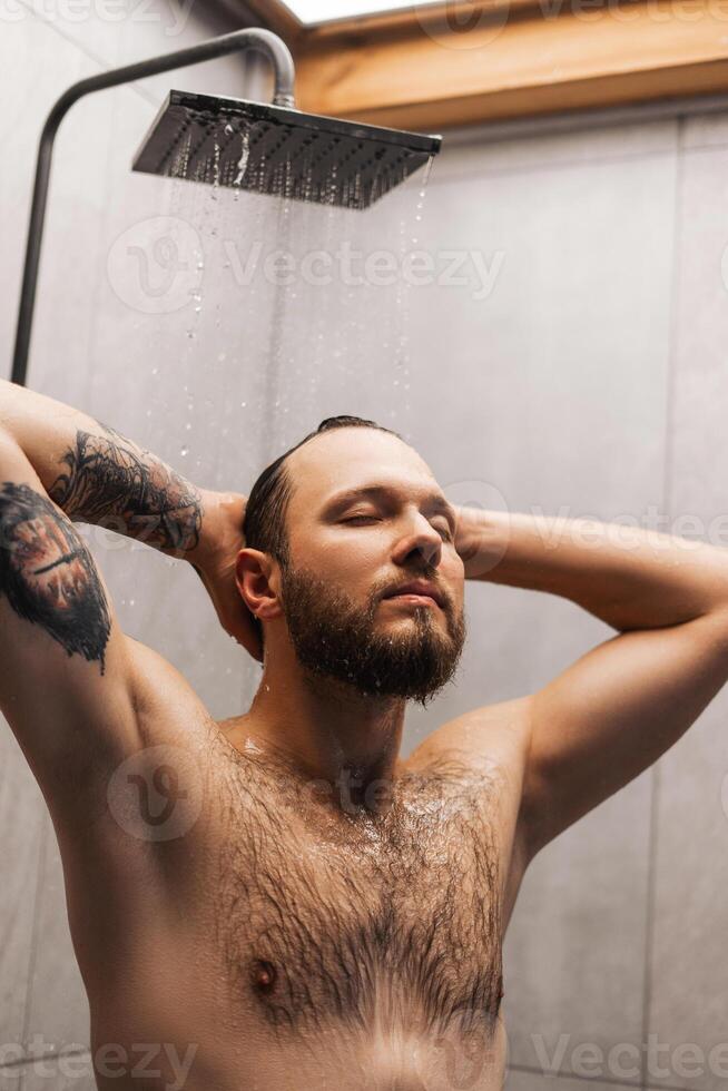 Young single handsome Caucasian man taking shower in the bathroom photo
