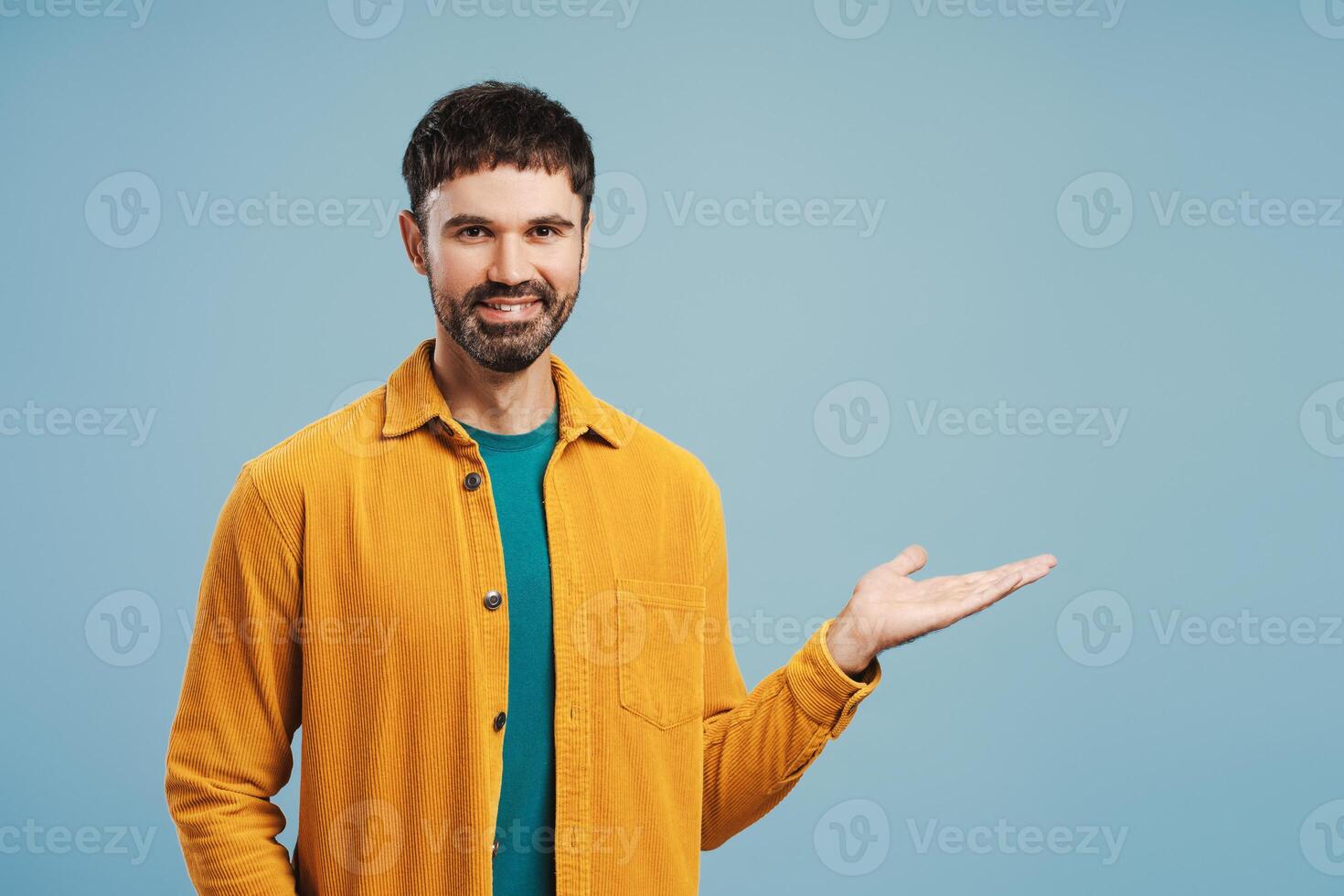 Portrait of middle aged Latin man wearing stylish yellow shirt showing with hand, looking at camera photo