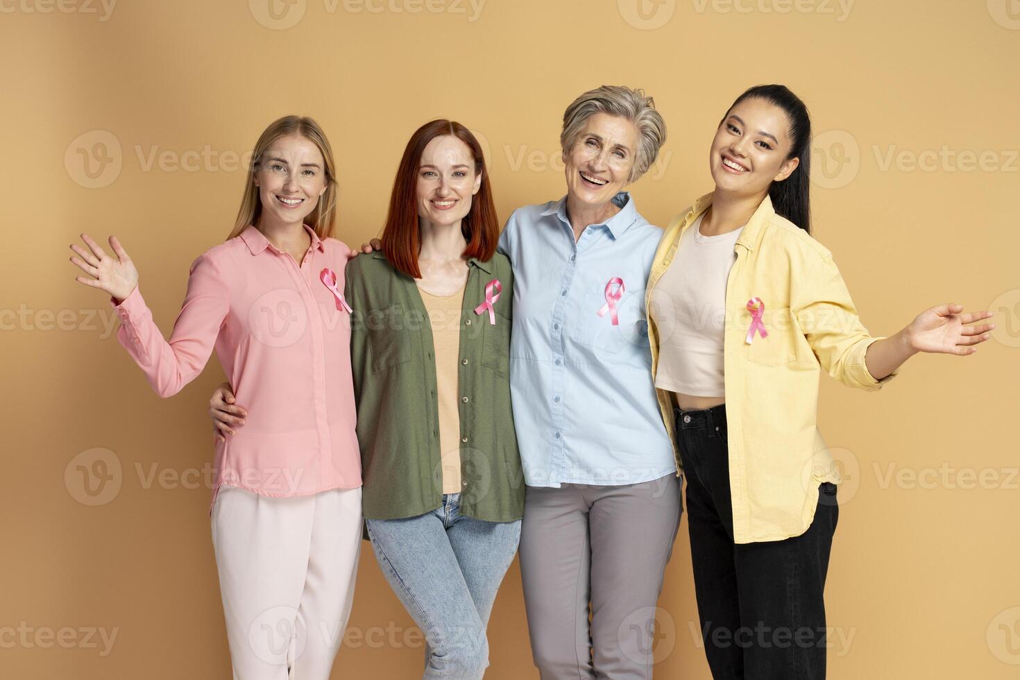Diverse women embracing and smiling wearing pink ribbons for breast cancer awareness photo