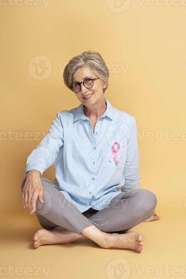 Senior woman smiling with pink ribbon showing support for breast cancer awareness photo